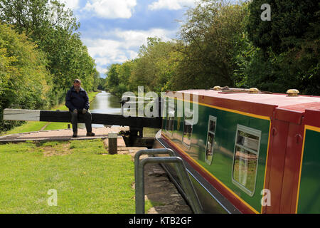 Man sitting on the arm of a lock, Stratford-on-Avon Canal, Warwickshire Stock Photo