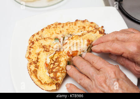 Omelet preparation : Rolling up the stuffed  omelet Stock Photo