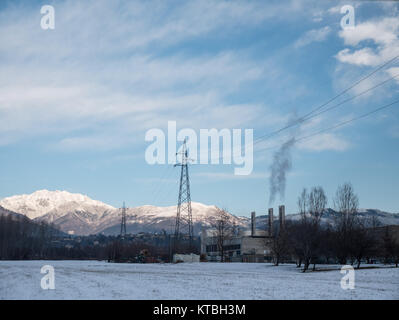 Biella, Italia - December 15, 2017: Industrial scenery covered by snow at the foot of the Alps, factory with chimneys that smoke, in the country of Bi Stock Photo