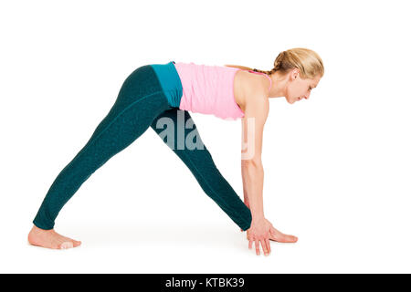 Seitliche Ganzkörper-Ansicht einer jungen Frau vor weißen Hintergrund eine Variation der Yoga-Übung Dreieck (Triconasana) zeigend. Stock Photo