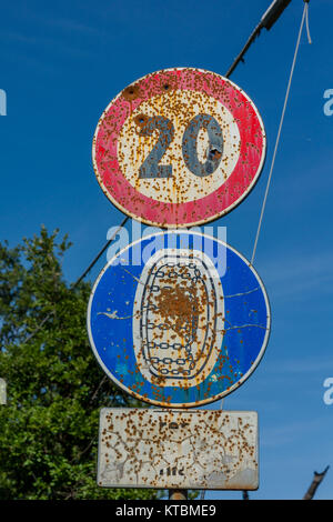 A rusted metal speed limit sign affixed to a tall metal pole in a rural ...