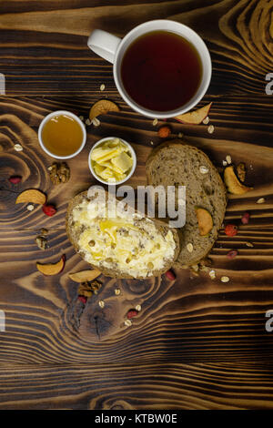 Two slices of bread, cup of tea and a cup of honey and butter, peanuts and decorated with pieces of dried apple lying on a wooden background Stock Photo