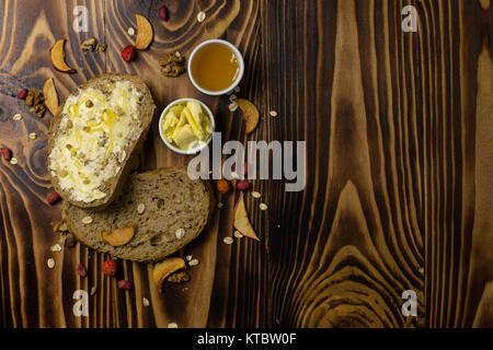 Two slices of bread and a cup of honey and butter, peanuts and decorated with pieces of dried apple lying on a wooden backgroundt are the wooden background Stock Photo