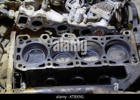 The cylinder block of the four-cylinder engine. Disassembled motor vehicle for repair. Parts in engine oil. Car engine repair in the service Stock Photo