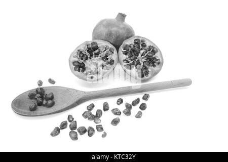 Pomegranate and two cut halves with seeds removed with spoon Stock Photo