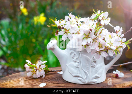 Branches of flowering almonds in a ceramic vase in the sun on a wooden surface Stock Photo