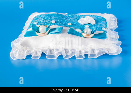 Wedding rings on a satin blue cushion on a blue background Stock Photo