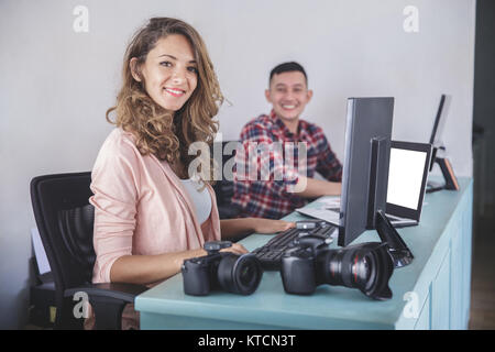 two photographers smiling while editing photos in their computer Stock ...