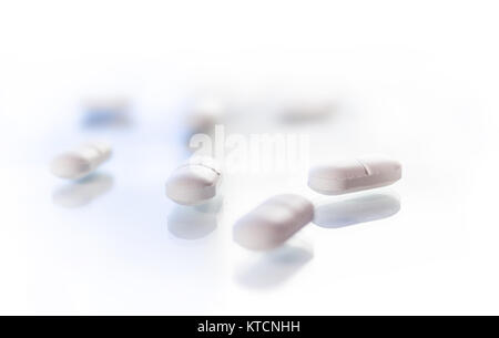 White tablets isolated on glass reflective surface Stock Photo