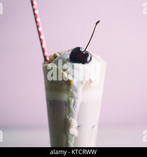 Tall root beer float with a fresh cherry on top and red straw with hearts. Close up shot. Stock Photo