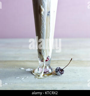 Messy, tall root beer float melting with fallen fresh cherry garnish. Vanilla ice cream dripping down the sides. Pastel background. Copy space. Stock Photo
