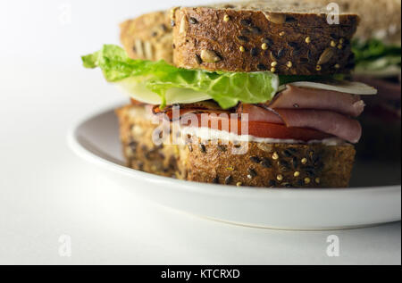 Ham sandwich made with artisan bread on a white plate. Copy space. White background. Stock Photo