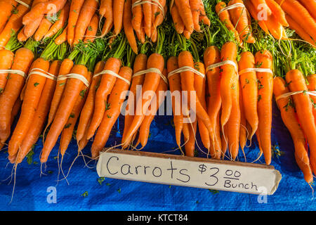 Carrots for sale at a vendor's stall at the Santa Barbara farmer's market vegetables. The carrot (Daucus carota subsp. sativus) is a root vegetable, u Stock Photo