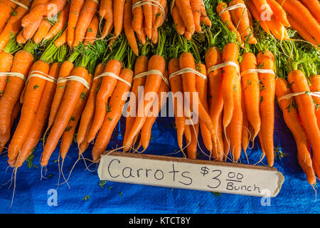 Carrots for sale at a vendor's stall at the Santa Barbara farmer's market vegetables. The carrot (Daucus carota subsp. sativus) is a root vegetable, u Stock Photo