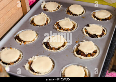 Mince pies in a baking tin ready to put into the oven. They are a festive snack, traditionally eaten around Christmas. Stock Photo