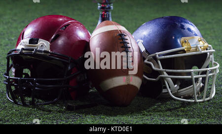 closeup shot of american football,helmets and trophy on grass field at night Stock Photo