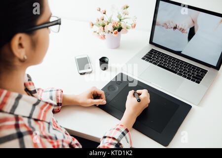 woman retouching on computer laptop using digital tablet and stylus pen Stock Photo