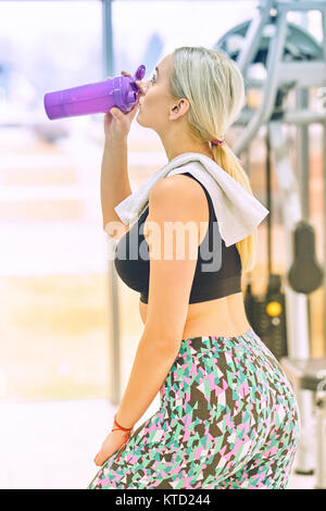 Professional bodybuilding athlete relax after exhausting training. Athlete relax and drink water from sport bottle in gym interior. Stock Photo