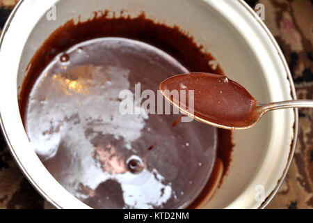 Tasty melted chocolate in a spoon and a white saucepan. Stock Photo