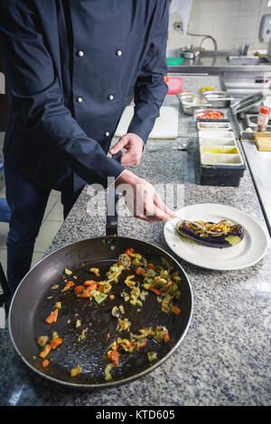 Chef in Restaurant garnishing vegetable dish, crop on hands, filtered image Stock Photo
