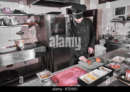 Chef sprinkling spices on dish in commercial kitchen Stock Photo