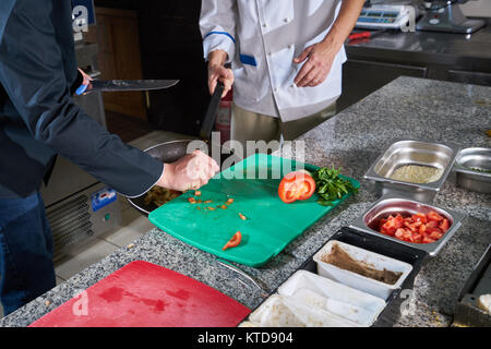 Chef sprinkling spices on dish in commercial kitchen Stock Photo