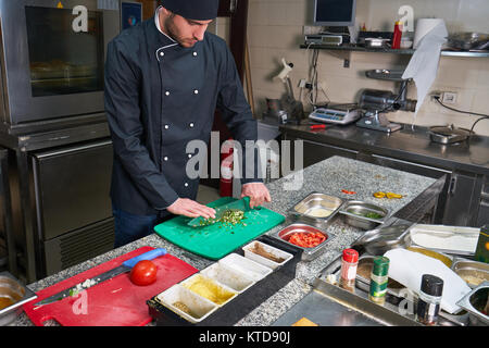 Chef sprinkling spices on dish in commercial kitchen Stock Photo