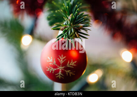 Close up of a red decorated ball hanging on a Christmas tree. Stock Photo