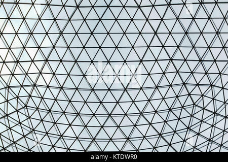 metal and glass atrium roof in repeating symmetrical triangualar pattern, shown with light coming through Stock Photo