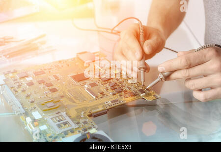 Computer repair service; hands of male tech testing motherboard Stock Photo