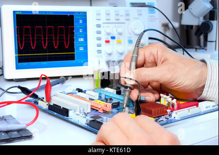 Tech tests electronic equipment in service centre Stock Photo