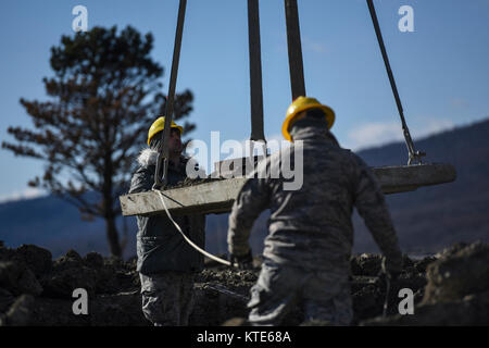 U.S. Air Force Staff Sgt. James Terrell, left, and Senior Airman Bobby Chambers, students attending an Engineering Installation vehicle training class, guide a maintenance hole cover in place Dec. 13, 2017, at the Air National Guard Schoolhouse, Fort Indiantown Gap, Pennsylvania. The course was inteded to provide EI Airmen with training and experience on multiple pieces of excavating equipment to help improve their mission readiness. (U.S. Air National Guard Stock Photo