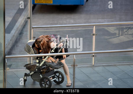 Young asian mother with child in pram at bus station Stock Photo