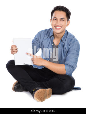 Young asian man pointing at something on the tablet pc, while si Stock Photo