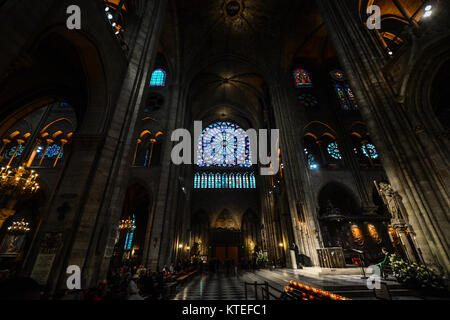 Services at Notre Dame Cathedral in Paris France highlighting the dramatic lighting at the altar with many stained glass windows and the Rose Window Stock Photo