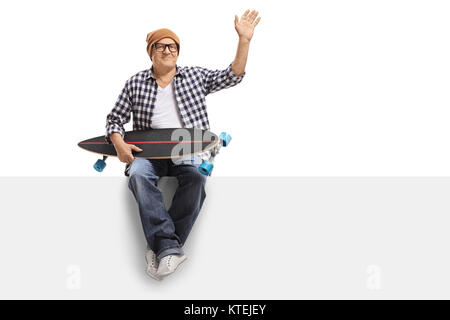 Old hipster with a longboard sitting on a panel and waving isolated on white background Stock Photo