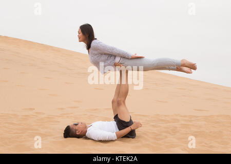 An Indonesian girl and Filipino boy doing a front bird yoga exercises on Dune 7, the highest sand dune in the world, in Walvis Bay, Namibia Stock Photo