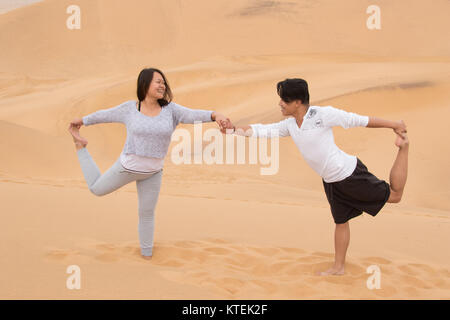 An Indonesian girl and Filipino boy doing yoga exercises on Dune 7, the highest sand dune in the world, in Walvis Bay, Namibia Stock Photo