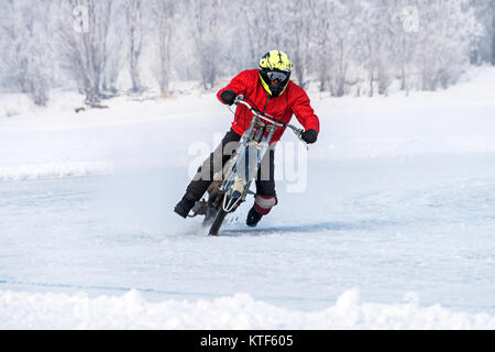 Motorcyclist unmarked travels with great speed across the ice on a winter bike with studded wheels. Competition for the Speedway in the winter. danger Stock Photo