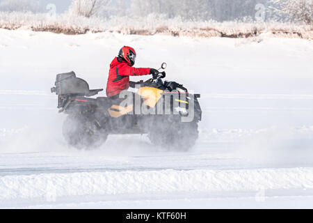 Unidentified motocross rider on quad bike at Opening motocross season race. winter motocross. ATVs are riding in the field in the snow on the backgrou Stock Photo