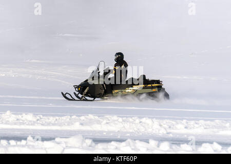Man driving sports snowmobile in Finnish Lapland in a sunny day. snowmobile in a field in the snow. Competitions on snowmobiles. Winter extreme entert Stock Photo