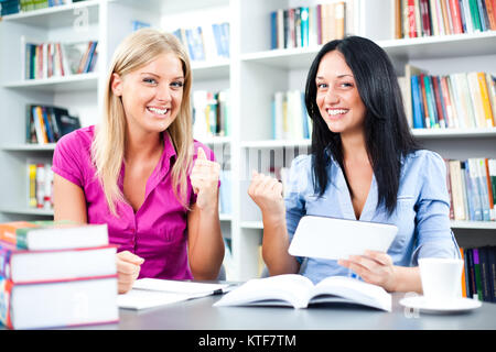 Students learning in library, using digital tablet Stock Photo