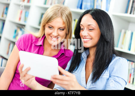Students learning in library, using digital tablet Stock Photo