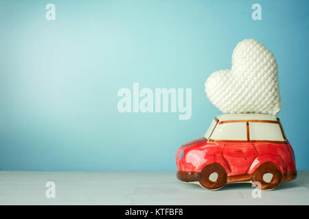 Miniature red car carrying a white heart on a cyan background Stock Photo