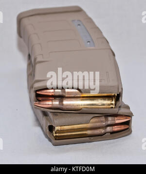 Two loaded .223 rifle magazines stacked on top of each other on a white background. The magazines are stacked in opposite directions from one another. Stock Photo