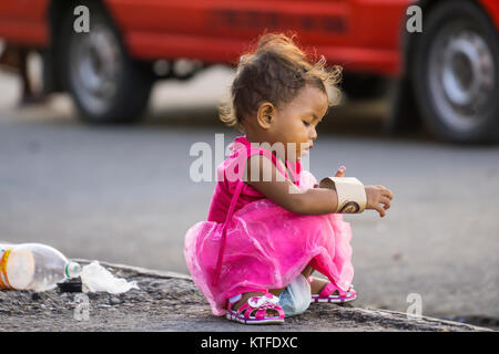 A young Filipino child playing with a paper cup holder on Christmas Day morning 2017,sidewalk,Cebu City,Philippines Stock Photo