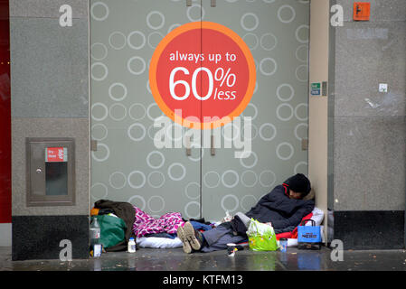 Glasgow, Scotland, UK  24th December.UK Weather: Rain and wind greet the last minute Christmas Eve shoppers to Buchanan street, Glasgow's style mile with homeless people on the street. Credit Gerard Ferry/Alamy news Stock Photo