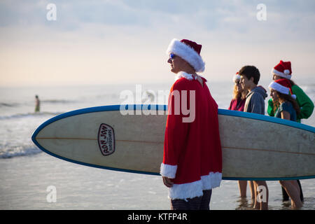 Cocoa Beach, Florida, USA. 24th Dec, 2017. Surfing Santas, an annual surf event taking place on Christmas Eve in Cocoa Beach, Florida where people dressed in Santa Claus costumes surf. Credit:  Lori Barbely/Alamy Live News Stock Photo