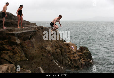 Sandycove, Ireland. 25th December 2017. People take part in the annual tradition of jumping into the forty foot, an open-sea bathing area, in Sandycove, Co Dublin. Credit : Laura Hutton/Alamy Live News. Stock Photo
