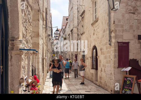 Black dressed woman with hat and many tourists walk on street in Dobrovnik old town. It is a city in southern Croatia fronting the Adriatic Sea. Stock Photo